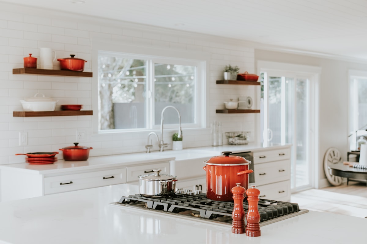 Grand white kitchen with marble waterfall island and drum pendants